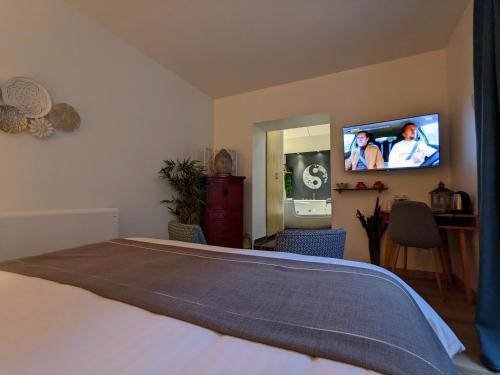 a bedroom with a bed and a tv on the wall at Chambres d'Hôtes La Filature in Saint-Quentin