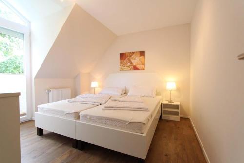 sypialnia z białym łóżkiem i oknem w obiekcie Am Wintershof 5 Whg 6 w mieście Kellenhusen