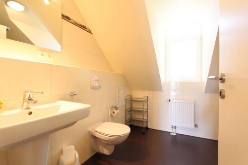 biała łazienka z umywalką i toaletą w obiekcie Am Wintershof 5 Whg 6 w mieście Kellenhusen