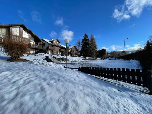 a snow covered street with houses and a fence at Les Prairies du lac in Gérardmer