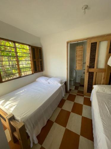 a bedroom with two beds and a checkered floor at älanacasadeplaya in San Bernardo del Viento