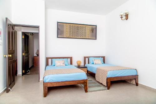 2 camas en una habitación con paredes blancas en Riverside Mount Simpson - Seychelles Island en Mahe