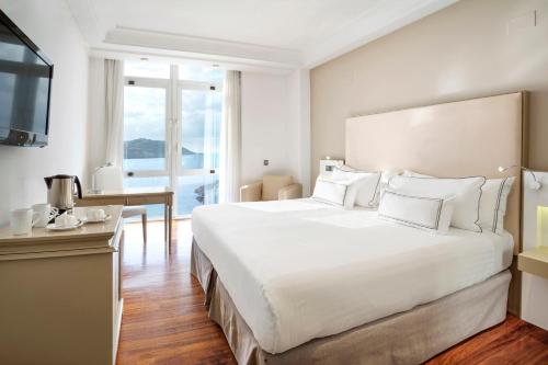 a hotel room with a large white bed and a desk at Melia Maria Pita in A Coruña
