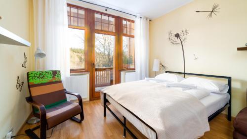 a bedroom with a bed and a chair and a window at Prywatne apartamenty z mini SPA, Sun & Snow in Szklarska Poręba