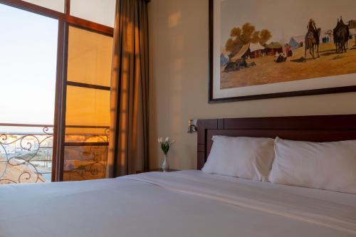 a bedroom with a white bed and a window at Al Ayjah Plaza Hotel in Sur