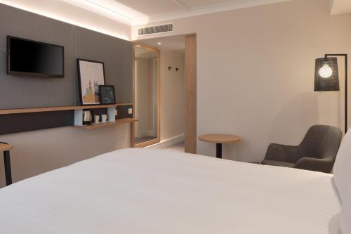 a hotel room with a white bed and a chair at Holiday Inn Bolton Centre by IHG in Bolton