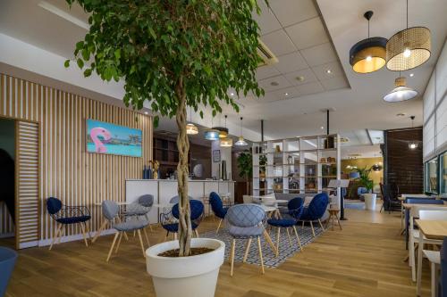 a waiting room with blue chairs and a tree in the middle at Best Western Plus Ajaccio Amirauté in Ajaccio