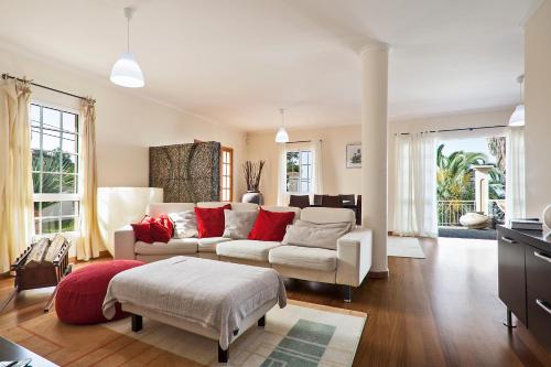 een woonkamer met een witte bank en rode kussens bij Capela - Casa das Neves in Funchal