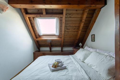 a bedroom with a white bed with a window at Asiago Millepini - Mansarda sull'Altopiano in Asiago