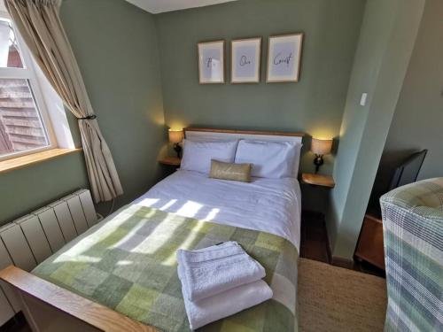 - une petite chambre avec un lit et des serviettes dans l'établissement Cosy Coppice Cottage, à Whitchurch