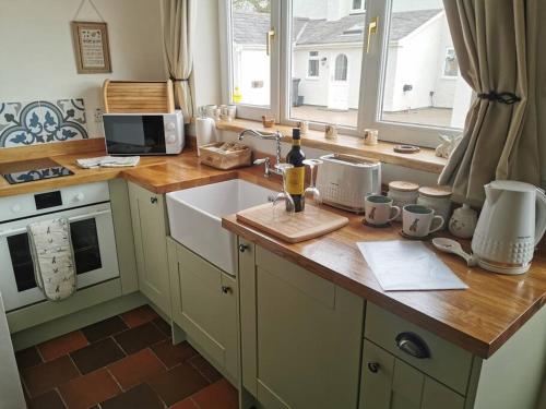 cocina con encimera con fregadero y ventana en Cosy Coppice Cottage en Whitchurch