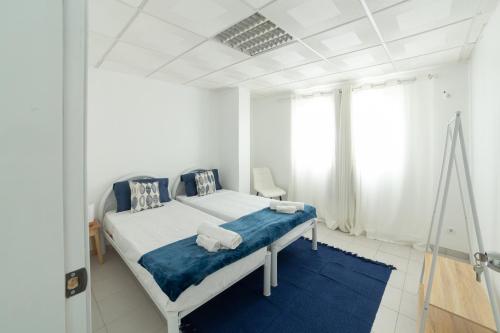 a white bedroom with a bed and a blue rug at A Casa da Mizi in Praia
