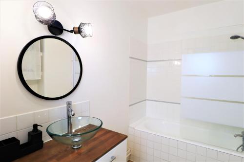uma casa de banho com um lavatório, um espelho e uma banheira em L'ECRIN Logement tout confort wifi, centre-ville, parking privé em Vannes