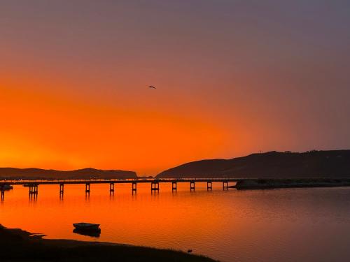 a bridge over the water with a sunset in the background at Paradise Found in Knysna