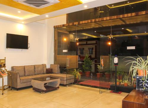 a living room with a couch and a tv at Sai Vihaar Inn & Suites in Mysore