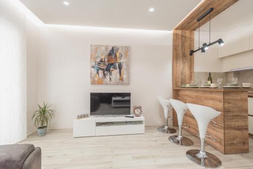 a living room with a fireplace and two white chairs at Apartment Ekatarina in Banja Koviljača
