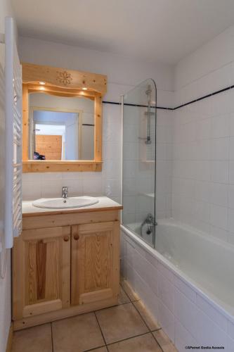 une salle de bain avec un lavabo, une baignoire et un miroir dans l'établissement Résidence Goélia Les Flocons d'Argent, à Aussois