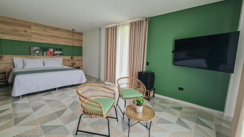 a hotel room with a bed and chairs and a television at Hotel Arbóreo Doradal in Doradal