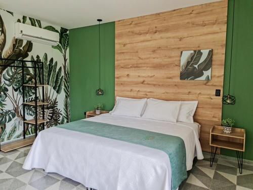 a bedroom with a large bed with green walls at Hotel Arbóreo Doradal in Doradal