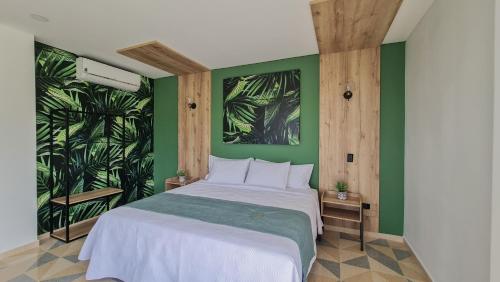 a bedroom with a large bed with green walls at Hotel Arbóreo Doradal in Doradal