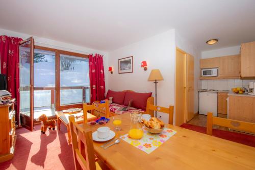 uma sala de estar com uma mesa e uma cozinha em Résidence Goélia Les Terrasses du Corbier em Le Corbier