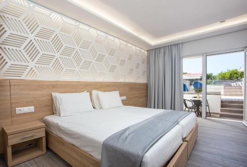 a bedroom with a large bed and a balcony at Tsampika Hotel Faliraki in Faliraki