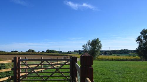 a wooden gate in a field with a fence at De Sint-Antoniushoeve in Zonnebeke