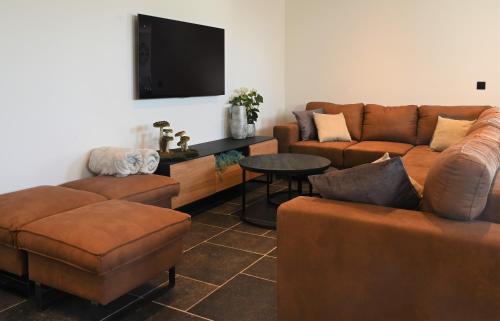 a living room with two couches and a tv at De Sint-Antoniushoeve in Zonnebeke