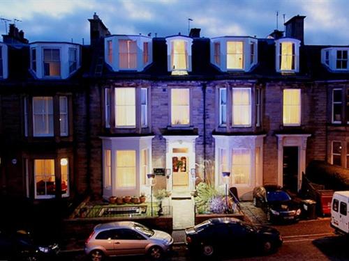 una casa grande con coches estacionados frente a ella en Hotel Ceilidh-Donia en Edimburgo