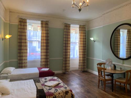 a bedroom with two beds and a table and a mirror at Thanet Hotel in London