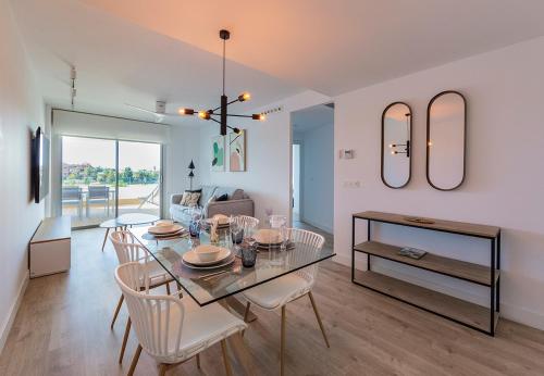 a dining room and living room with a table and chairs at Homity Exclusive Playa Granada Beach & Golf - Mar de Astrid in Motril