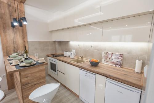 a kitchen with white cabinets and a wooden counter top at Apartment Ekatarina in Banja Koviljača