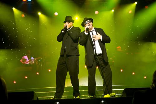 two men standing on a stage singing into microphones at Lærdal Ferie- og Fritidspark in Lærdalsøyri