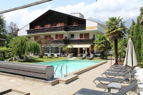 een hotel met een zwembad en stoelen en een gebouw bij Garni Weingut in Merano