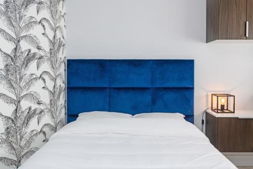 a bed with a blue headboard in a bedroom at The City Nest - Duke Housing in Créteil