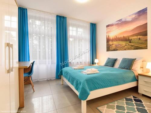 sypialnia z łóżkiem z niebieskimi zasłonami i biurkiem w obiekcie WILLA DobraNocka w Szklarskiej Porębie