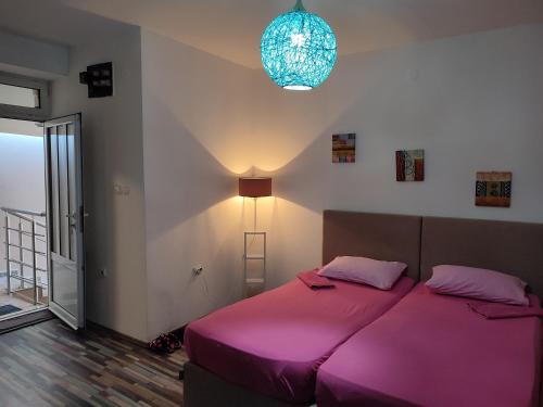 a bedroom with a large bed with a pink blanket at V&J apartments in Podgorica