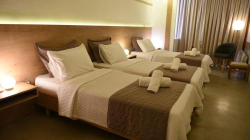 Habitación de hotel con 3 camas con almohadas blancas en Hotel Xanthippion, en Xanthi