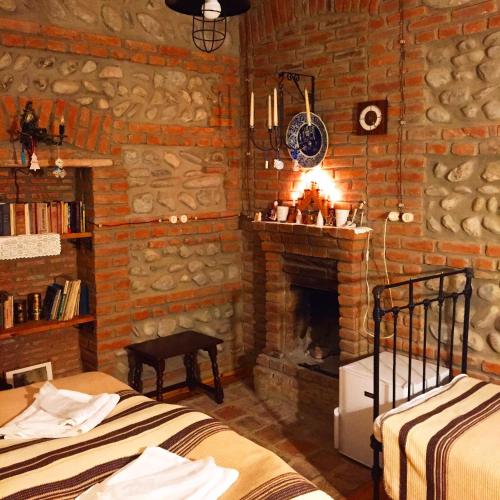 a room with two beds and a brick fireplace at Dzveli Galavani -Old Wall in Tʼelavi