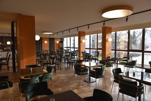 a restaurant with tables and chairs and windows at Hotel Xanthippion in Xanthi