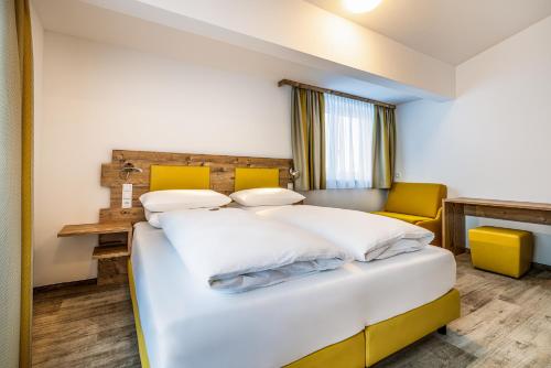 a bedroom with a white bed and yellow chairs at Der Alpenblick in Sankt Johann im Pongau