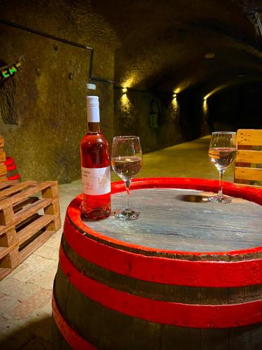 a bottle of wine and two wine glasses on a barrel at Zöld Sziget Üdülőház in Egerszalók