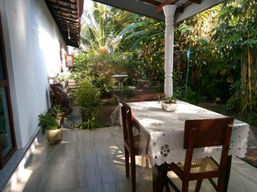 einen weißen Tisch und Stühle auf einer Terrasse mit Bäumen in der Unterkunft Sisila Villa in Bentota