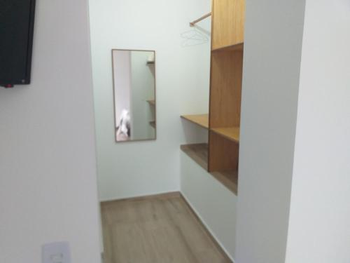 a hallway with a mirror and a white wall at Vilarejo da Esperanza in Campos do Jordão