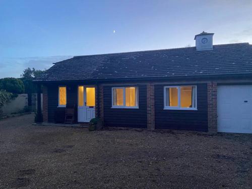 a small brick house with its lights on at The Annex, Truffles, West Wittering in West Wittering