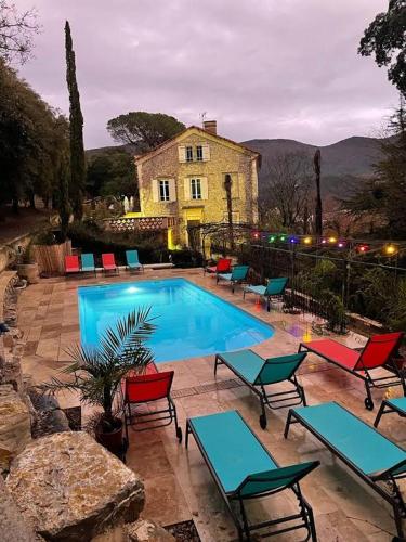 a swimming pool with chairs and a house in the background at Les Horizons - SPA-JACUZZI - MASSAGE- SAUNA - 4 SAISONS - Piscine chauffée Toute l'année - 800m centre ville Nyons in Nyons