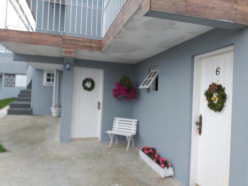 a porch of a house with a bench and flowers at Vilarejo da Esperanza in Campos do Jordão