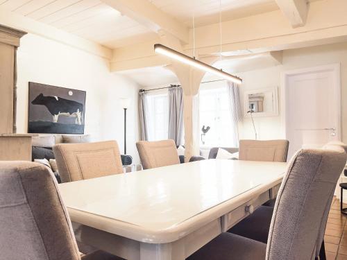 a dining room with a white table and chairs at Föhrienhaus in Midlum