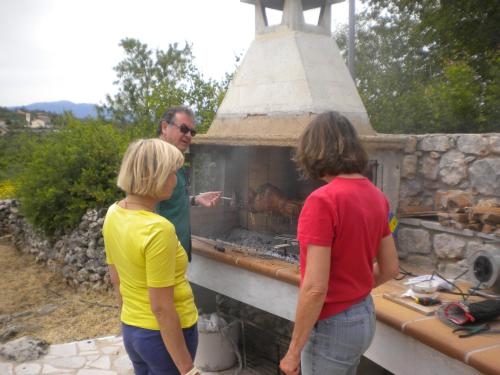 two women and a man cooking food in an outdoor oven at Amygdalia, a Stone House in a quiet landscape in Leonidion