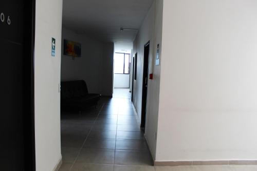 a hallway with a white wall and a tile floor at Hotel America 52 in Rionegro